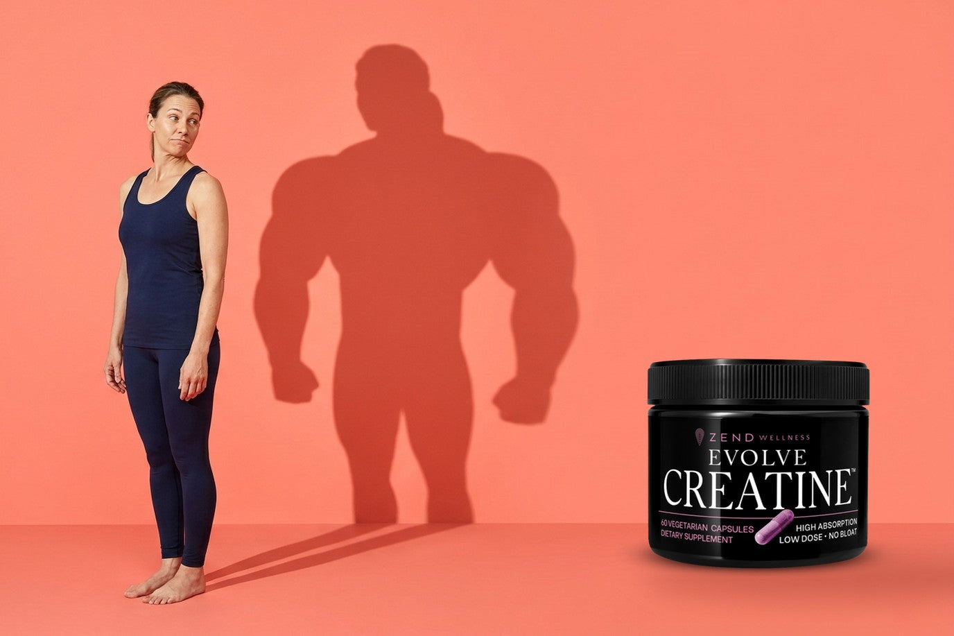 A woman looking, unimpressed, at her own cast shadow, which is twice her width and heavily built, with the Evolve Creatine jar beside her