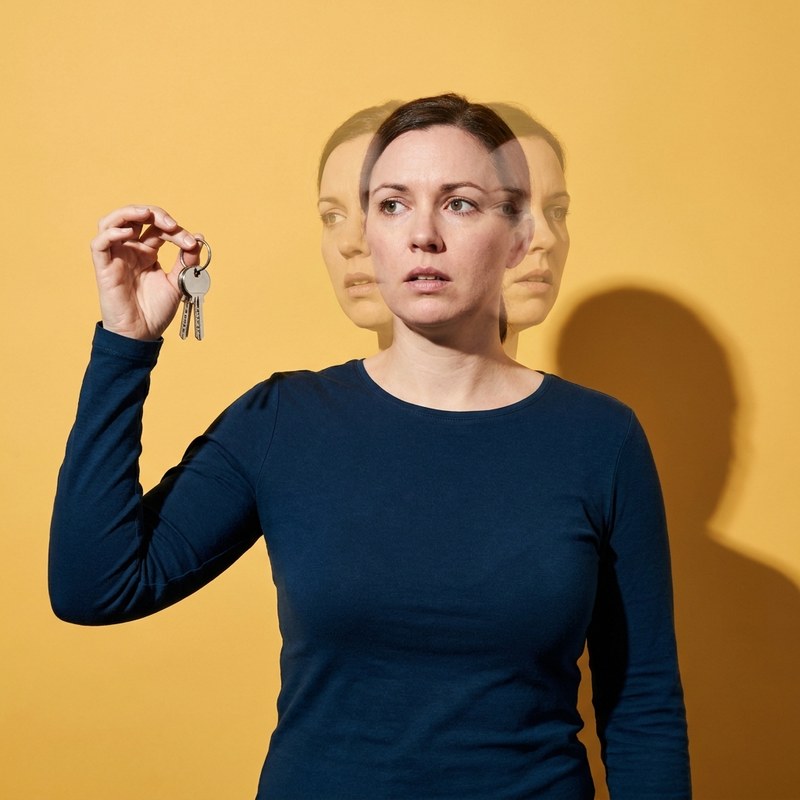 A woman standing beside her own shadow on the wall, the shadow far larger and heavier than she is