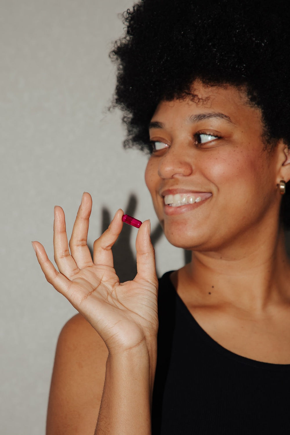 A smiling woman holding a single pink Evolve capsule