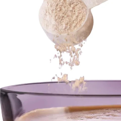 A scoop of MetaGlow powder pouring into a cup of coffee